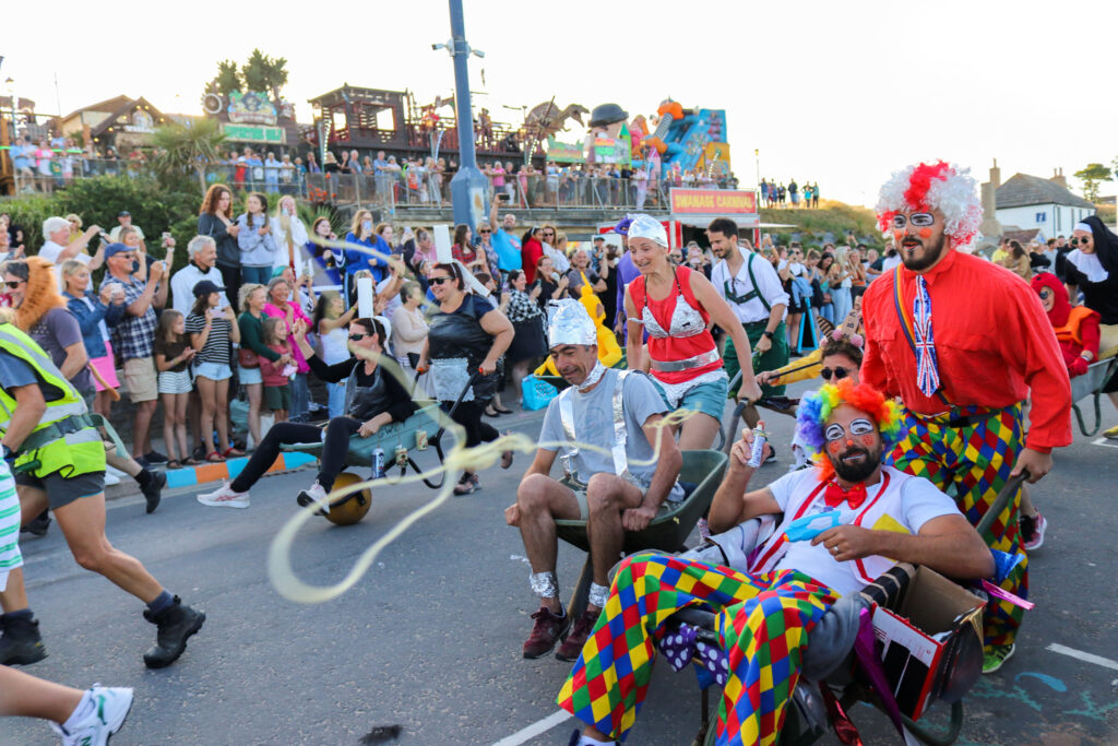 People in fancy dress as clowns at Swanage Carnival wheelbarrow race