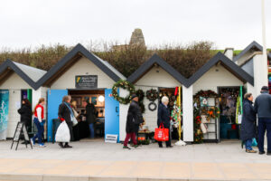 Tourists and locals browsing Swanage beach huts